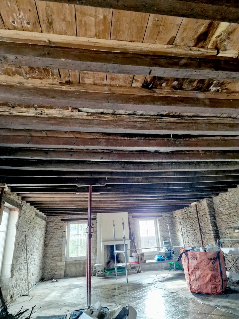 Charpente ancienne mise à nu, poutres et solives d’origine, mur en pierre brute, avant tout doublage