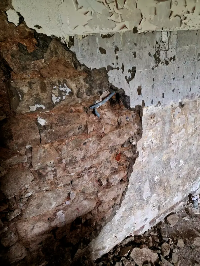 Mur piqué, ancien enduit tombé, pierre et moellons réapparus sous le plâtre