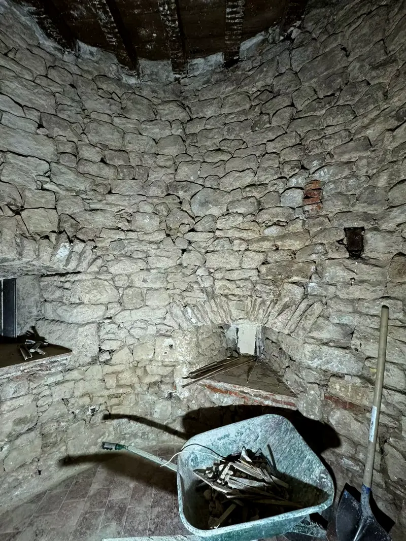 Intérieur de la tour ronde, paroi en pierre appareillée, niche et corbeaux dégagés, plancher haut en bois laissé apparent