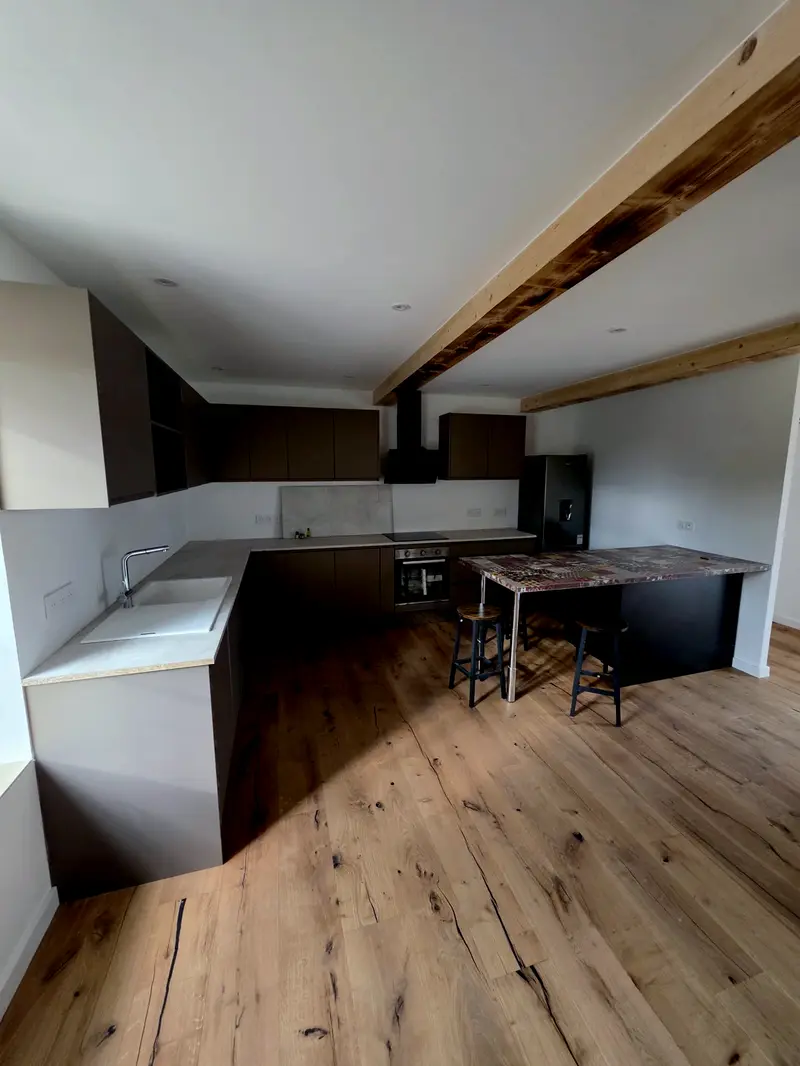 La même cuisine prise dans l'autre sens, hotte encastrée dans le meuble haut, four et plaque alignés sur le plan de travail