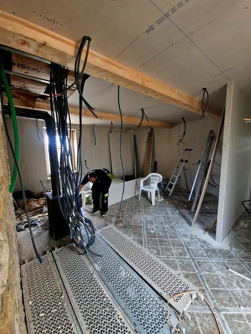 Gaines électriques le long d’un poteau bois, câbles au sol avant cloisons