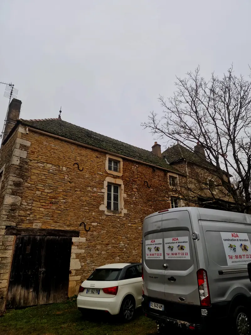 Le fourgon d'ADA Construction, marqué au nom et au numéro de l'entreprise, garé devant un bâtiment en pierre