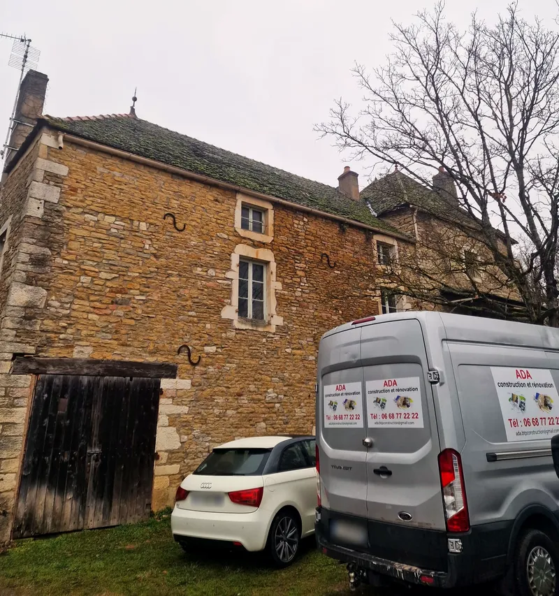 Le fourgon d’ADA Construction, marqué au nom et au numéro de l’entreprise, garé devant un bâtiment en pierre