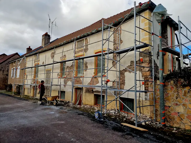 Façade de rue décroûtée sous échafaudage, pierre et brique apparentes